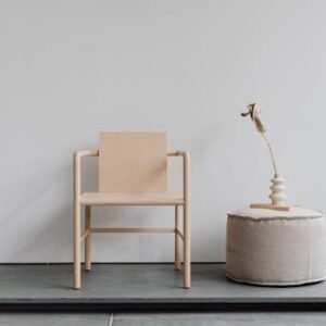 Simple yet elegant minimalist furniture featuring a wooden chair and pouf in a bright modern interior.